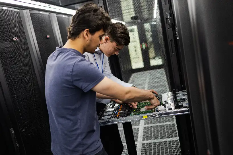 Deux techniciens datacenters intervenant sur un serveur dans un cold corridor d'un datacenter